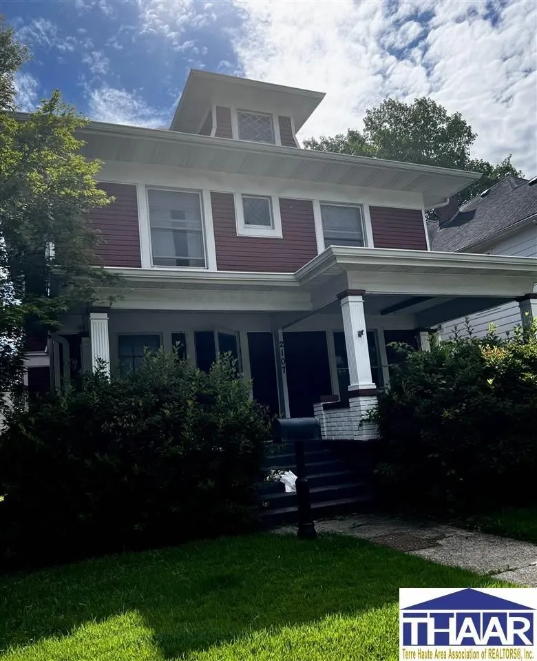 A large red house with a white trim and a porch.