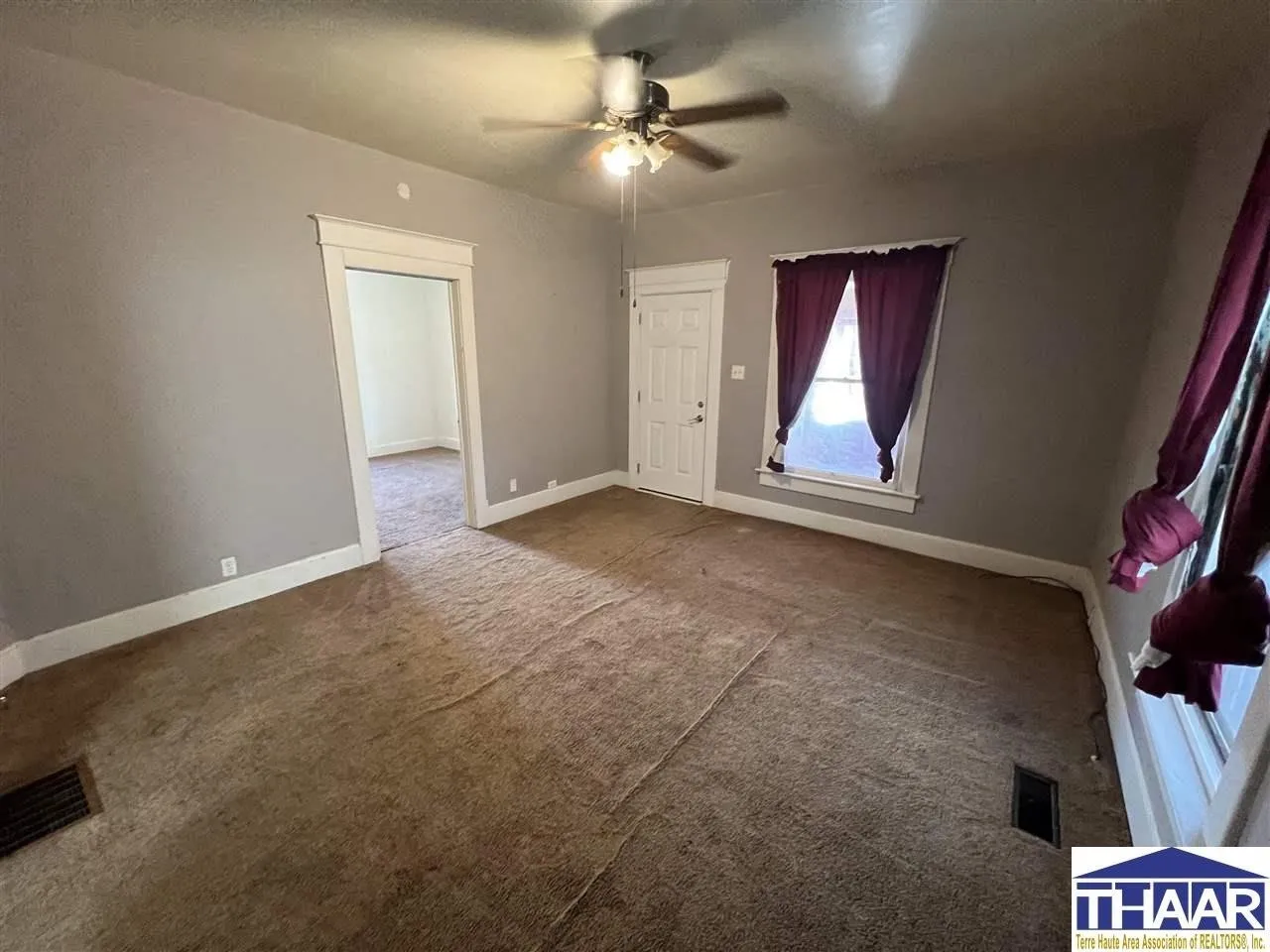 A room with a ceiling fan and carpet.