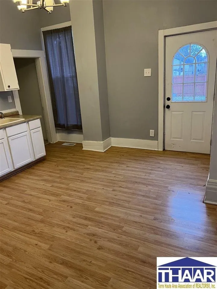 A room with hard wood floors and white cabinets.