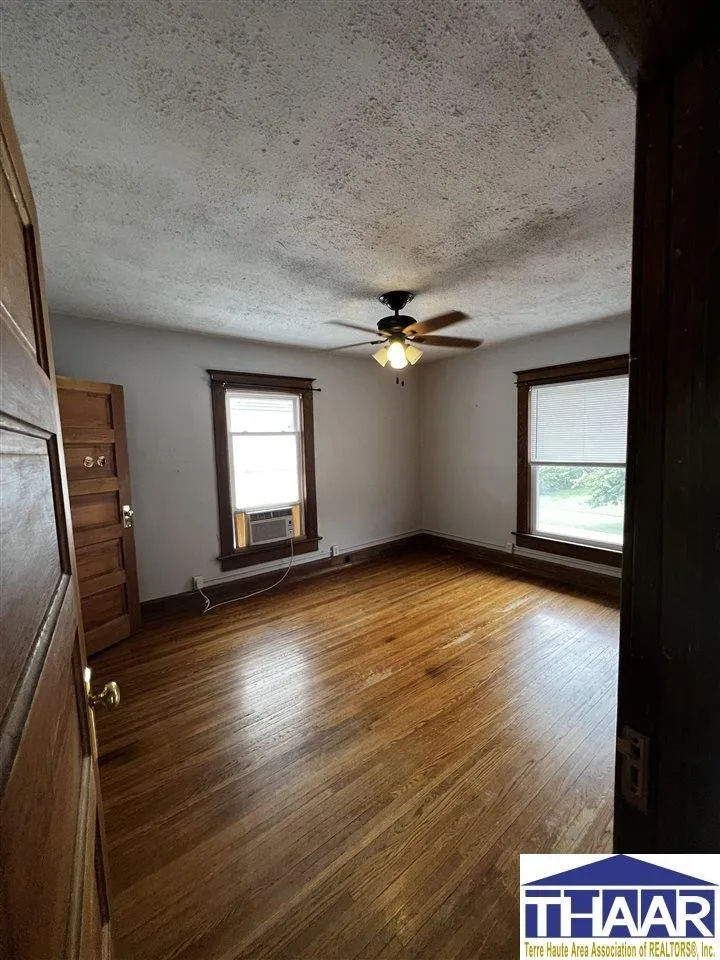 A room with wood floors and ceiling fans.