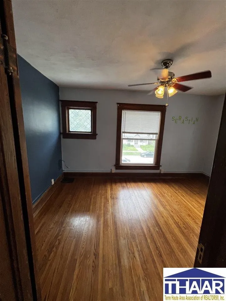 A room with wood floors and a ceiling fan.