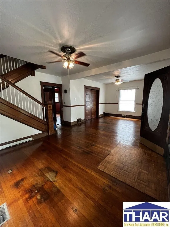 A large room with wooden floors and a ceiling fan.