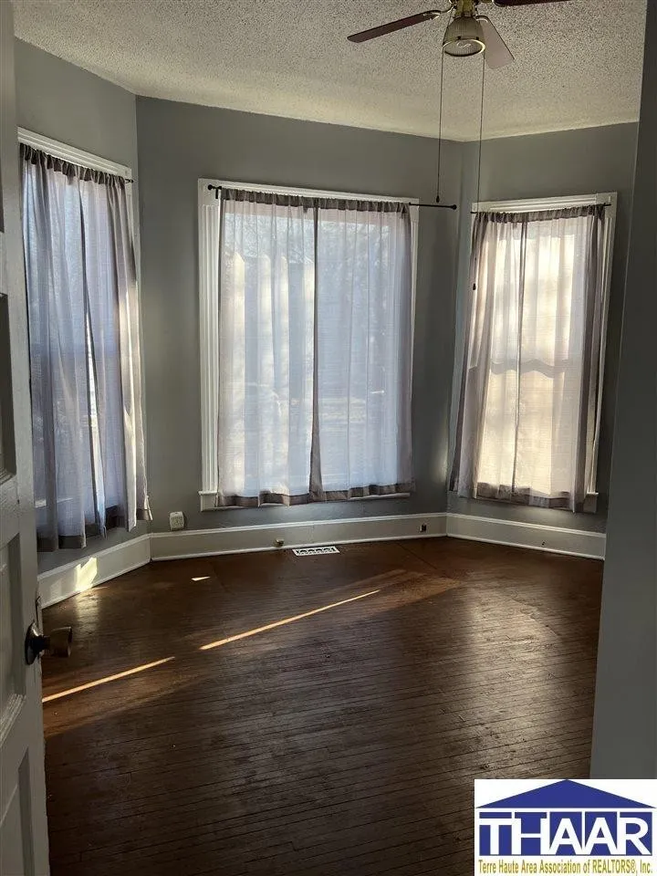 A room with two windows and a wooden floor.