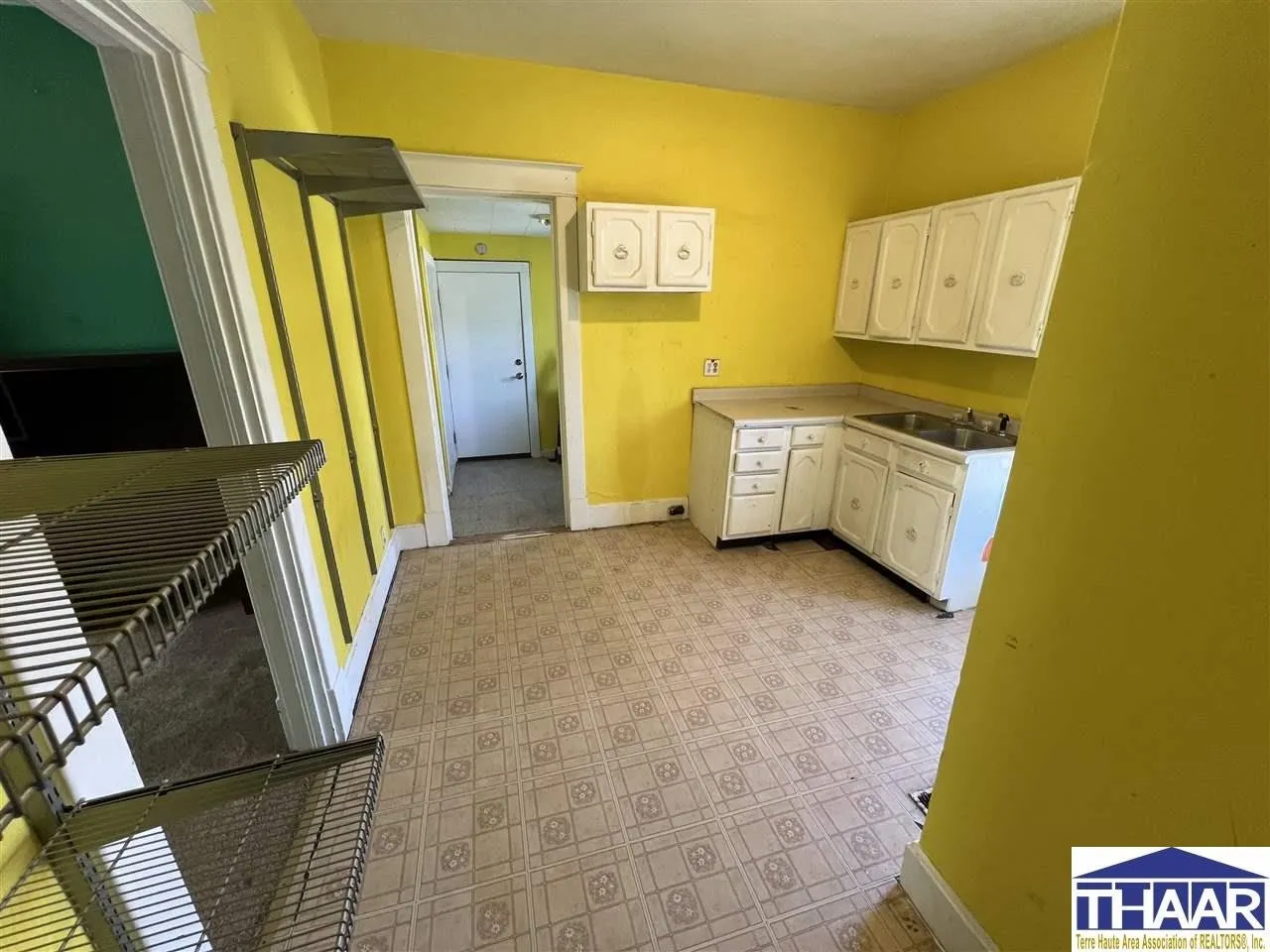 A kitchen with yellow walls and white cabinets.