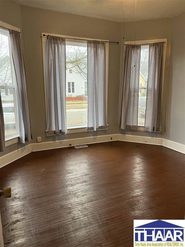 A room with two windows and a wooden floor.