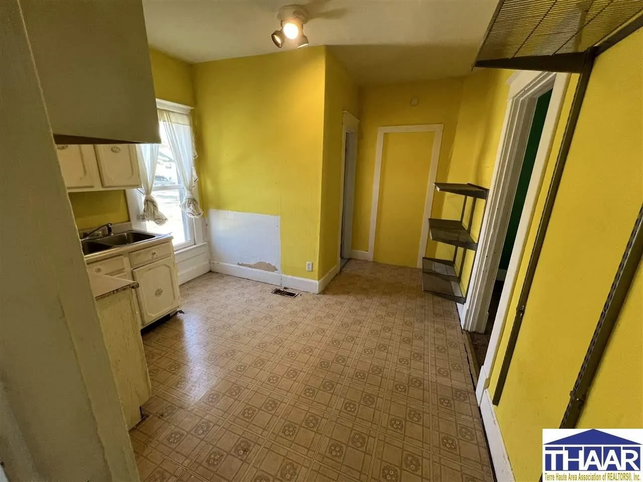 A kitchen with yellow walls and white cabinets.