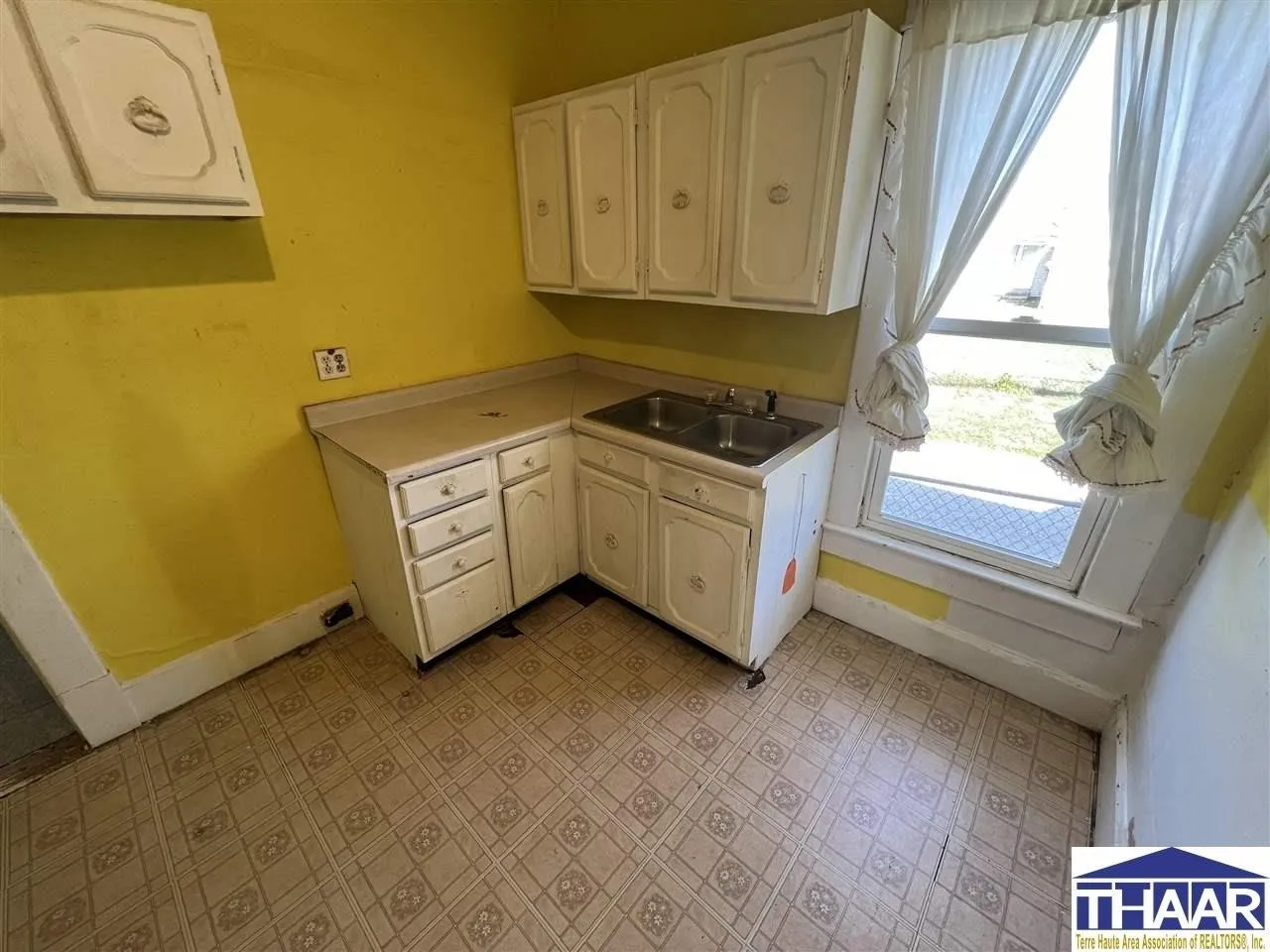 A kitchen with yellow walls and white cabinets.