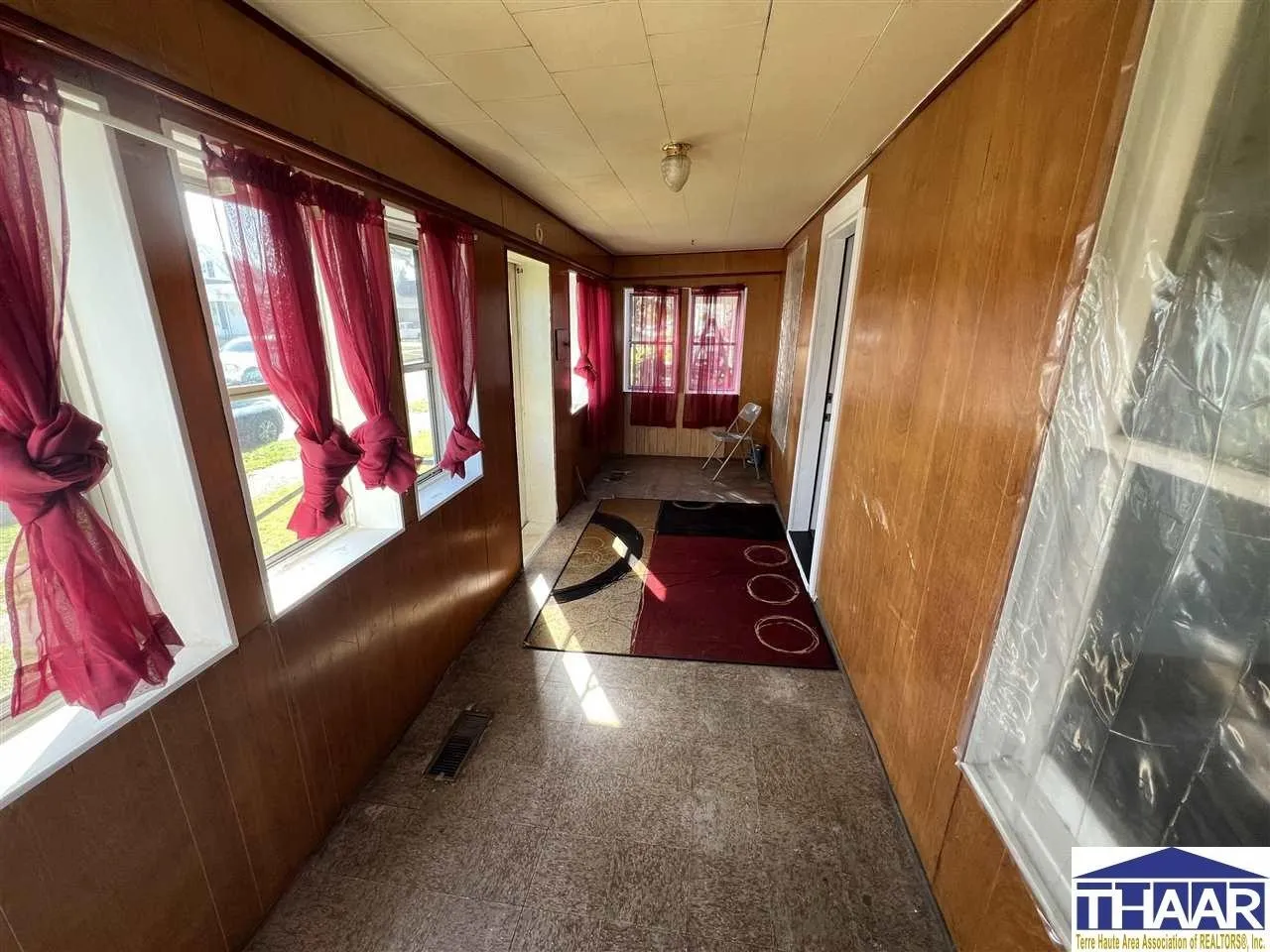 A hallway with red curtains and a rug.