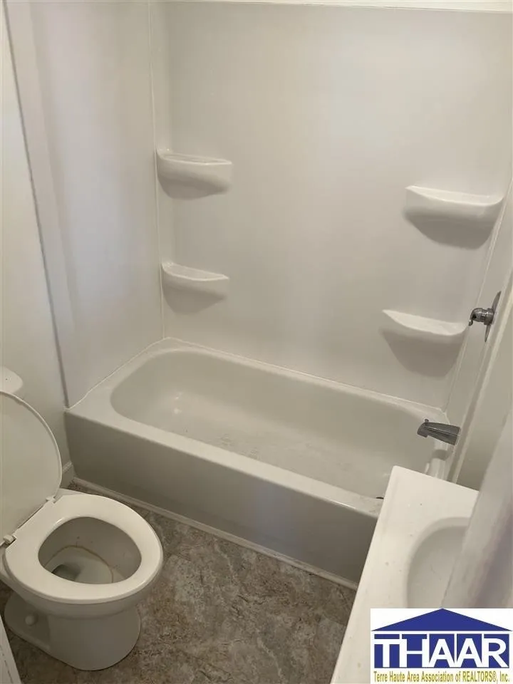 A bathroom with white walls and a toilet, bathtub, and sink.