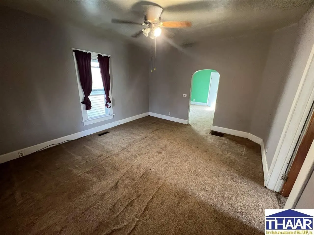 A room with a ceiling fan and a window.